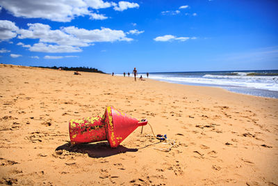 Red buoy on sand at beach blue sky