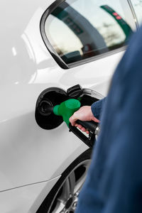 Cropped unrecognizable man refilling vehicle tank at petrol station during energy crisis