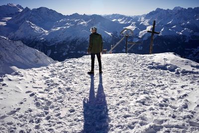 Rear view of person standing on snowcapped mountain