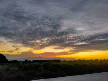 Scenic view of dramatic sky over land during sunset