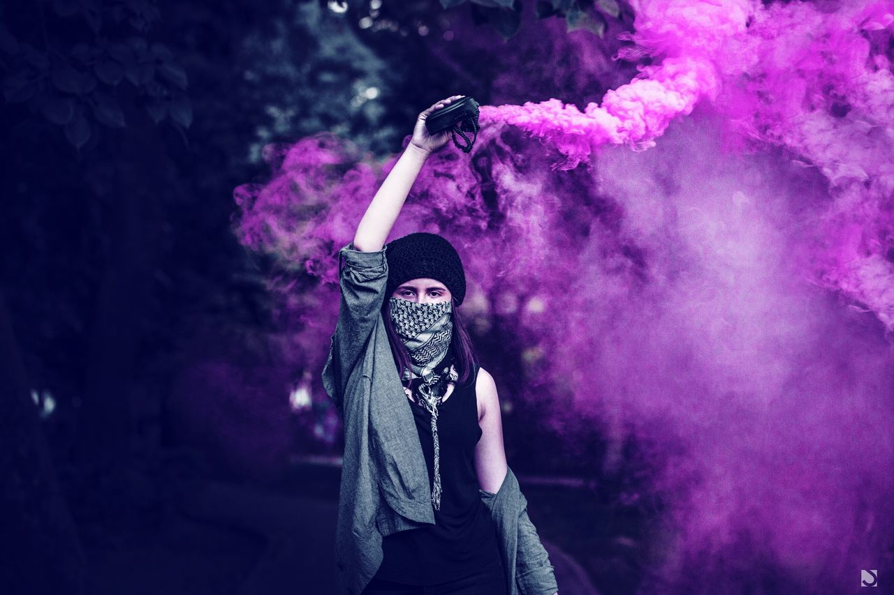smoke - physical structure, three quarter length, celebration, real people, one person, leisure activity, enjoyment, mask, event, men, front view, standing, lifestyles, adult, casual clothing, activity, festival, arts culture and entertainment, holding, obscured face, human arm, holi, nightlife