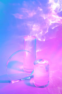 Two clear glass cylinder podiums on pastel neon background
