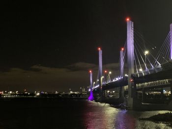 Illuminated bridge over river at night