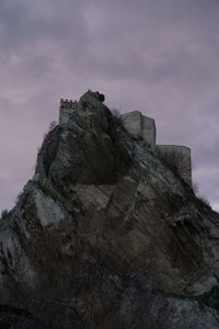 Low angle view of rock formation against cloudy sky