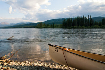 Boat in lake against cloudy sky