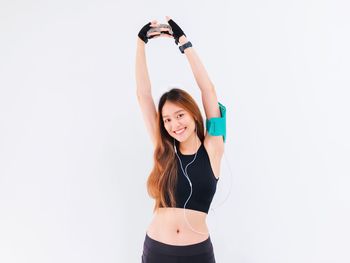 Portrait of smiling young woman standing against white background