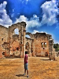 Full length of woman standing by old ruin against sky