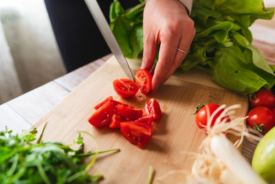 Cropped hands of man holding knife on cutting board