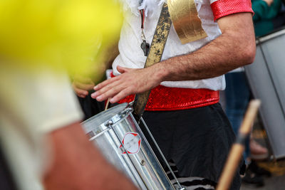 Midsection of man playing drum during festival