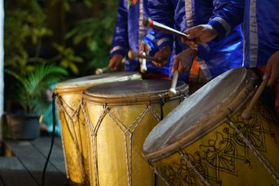 Midsection of men playing drum during event at night