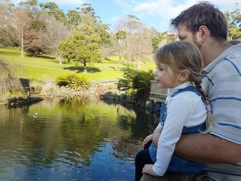 Father and daughter sitting by canal