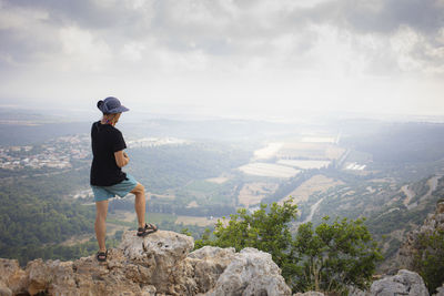 Man from behind standing on the edge of the mountain and watching a landscape. hiking concept.
