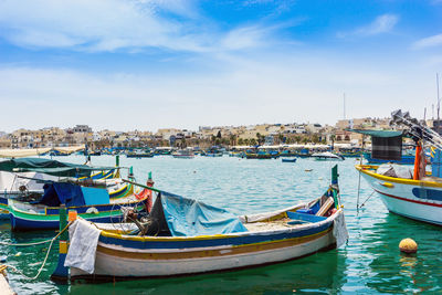 Boats moored at harbor against blue sky