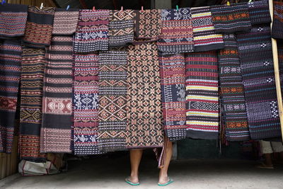 Low section of man standing by shawls hanging outdoors