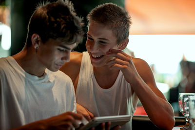 Smiling friends using digital tablet in restaurant