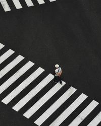 High angle view of man walking on zebra crossing at street