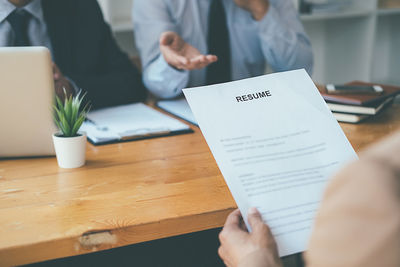 Midsection of man holding paper with text on table