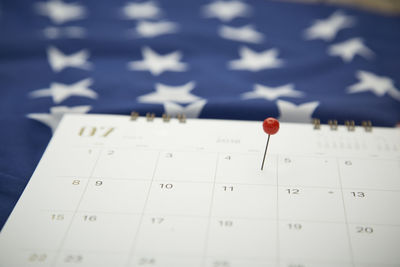 Close-up of thumbtack on calendar over american flag