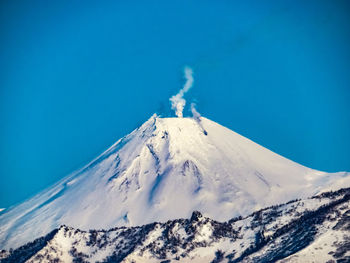 Scenic view of snowcapped mountains against clear blue sky