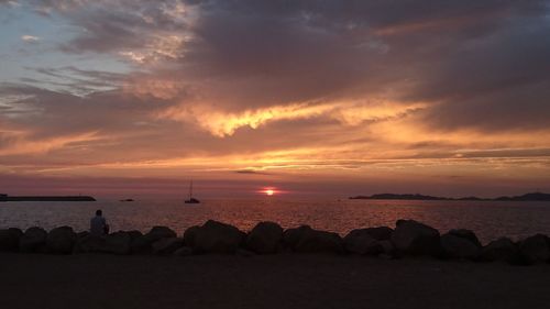 Scenic view of sea against cloudy sky during sunset