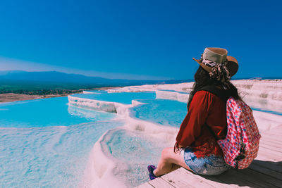 Rear view of woman looking at sea against blue sky