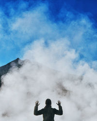 Low angle view of person standing against cloudy sky