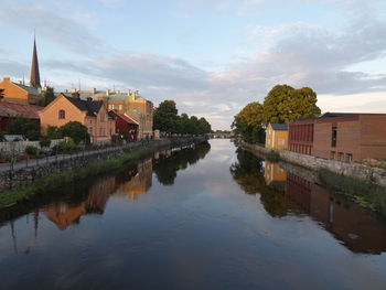 River amidst houses and buildings against sky