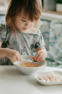 A little girl is sitting at the kitchen table eating soup. high quality photo