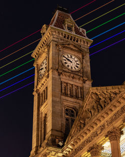 Low angle view of clock tower at night