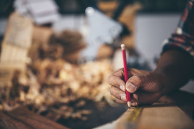 Cropped hand of carpenter holding pencil