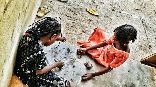 High angle view of girls with dreadlocks playing by wall