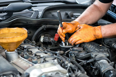 Cropped hands of mechanic repairing car at garage