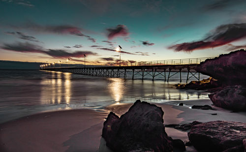 Bridge over sea against sky during sunset