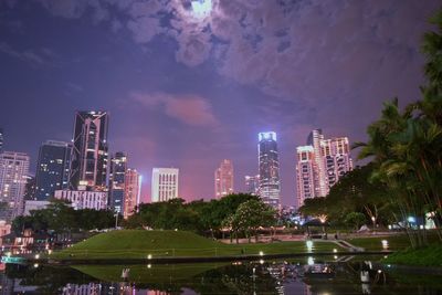 Scenic view of lake by cityscape against sky at night