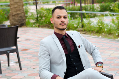 Portrait of confident businessman sitting on chair at patio