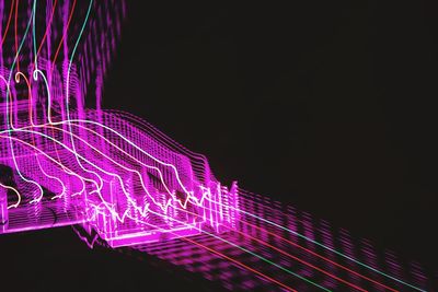 Light trails in city against sky at night