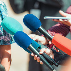 News microphones, reporters interviewing an unrecognizable people outdoors