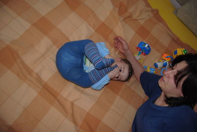 High angle view of mother and son lying on bed at home