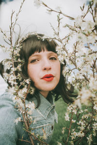 Portrait of woman against red flowering plants