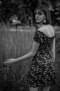 Portrait of smiling young woman standing at field