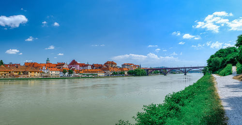 Scenic view of river by buildings against sky