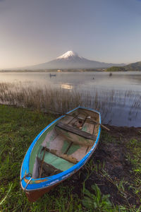 Boat moored by lake against mt fuji