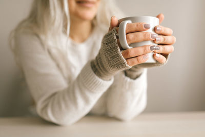 Midsection of woman holding coffee cup on table