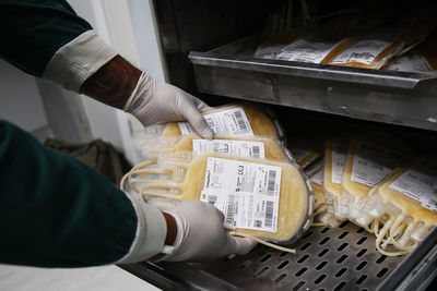 Cropped hands of doctor keeping blood bags in tray