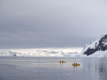 People on frozen lake against sky