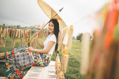 Side view of young woman holding umbrella on field