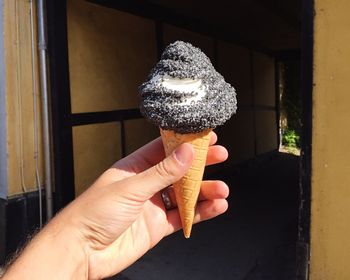 Cropped image of man holding licorice ice cream against doorway