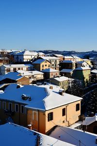 High angle view of houses in town against clear blue sky