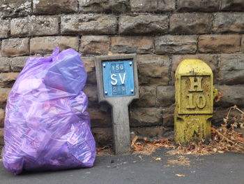 Garbage bin against stone wall