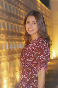 Side view of woman standing against illuminated wall